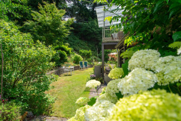 Der gepflegte Garten verfügt über gemütliche Gartenmöbel, Sonnenliegen und einen großen Sonnenschirm.