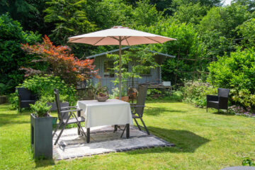 Der gepflegte Garten verfügt über gemütliche Gartenmöbel, Sonnenliegen und einen großen Sonnenschirm.