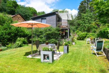 Der gepflegte Garten verfügt über gemütliche Gartenmöbel, Sonnenliegen und einen großen Sonnenschirm.